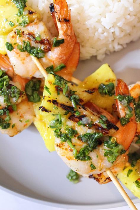 Using a cast iron grill pan, you can create flavorful and fragrant grilled shrimp and pineapple skewers from the comfort of your home kitchen. These skewers are topped with Chimichurri and served with a side of coconut rice, giving you the best Caribbean flavors. #thedailyspeshyl #skewers #shrimpskewers #coconutrice #pineapple | thedailyspeshyl.com Grilled Shrimp And Pineapple, Shrimp And Pineapple Skewers, Chimichurri Shrimp, Shrimp And Pineapple, Grilled Skewers, Pineapple Skewers, Pineapple Skewer, Cast Iron Grill Pan, Delicious Seafood Recipes