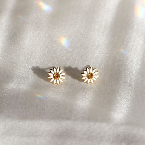 "Daisy stud earrings are so cute for the flower child! Hard enamel in bright white & yellow accented with polished gold. Wildflower + Co. ♥ Measures approx. ¼ \" ♥ Materials: dipped in gold plating, glitter flooded resin, & enamel. Posts are titanium - good for sensitive ears! ♥ Packaged in our cute gift box ♥ Designed by & exclusive to Wildflower + Co. ♥ Imported ♥ Product safety - intended for use by adults only; CA residents - see shop policies for Prop 65 warning ♥ Includes 1 pair of earring Daisy Earrings Studs, Earrings Cute Simple, Cute Earrings Aesthetic Stud, Daisies Earrings, Gold Cottagecore, Cute Earrings Aesthetic, Cottagecore Earrings, Statement Stud Earrings, Aesthetic Earrings