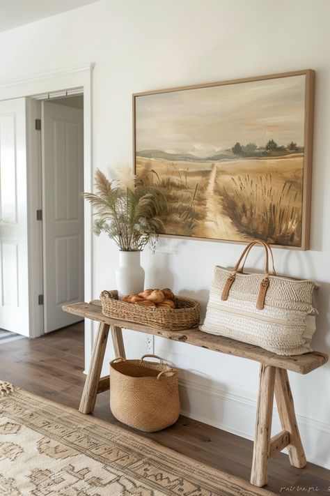 Rustic bench under a scenic painting embodies farmhouse wall decor, enhanced with natural baskets and a woven rug, creating a serene entryway. Dark Wood Farmhouse Decor, Neutral Rustic Decor, Minimalist Country Decor, Rustic Living Room Wall Decor Ideas, Sala Farmhouse, Farmhouse Minimalist Decor, Classy Farmhouse Decor, Minimal House Decor, Minimalist Cottage Decor