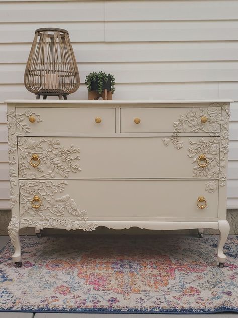 This gorgeous 100 year old dresser has been brought back to life! We called her 'Lady', and she will add a beautiful floral accent to any home. Adorned with hand-placed resin flowers and painted in Cathedral Taupe from Fusion Mineral Paint, Lady is a feminine yet versatile addition to your decor. Refinished gold hardware opens the deep, roomy, dovetailed drawers. The polyacrylic finish adds durability to this solid wood piece, and the casters make adding her to your space a breeze! Dresser Stickers Drawers, Iod Molds Dresser, Furniture With Flower Molds, Floral Dresser Diy, Resin Flowers On Furniture, Wood Applique On Furniture, Cottage Core Dresser, Dresser With Flowers, Taupe Dresser