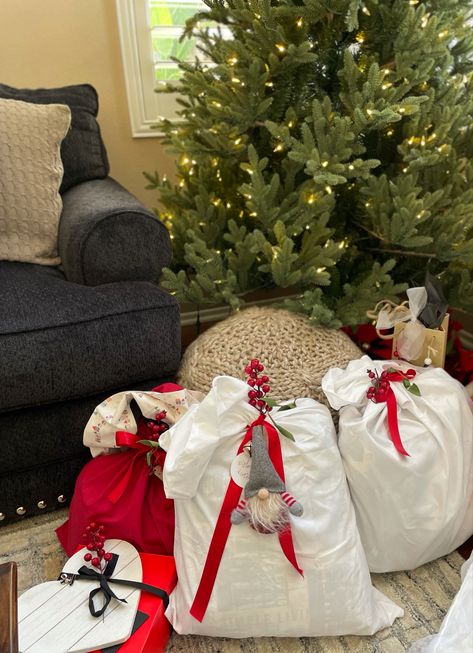 Sew a 15 minute “burrito pillowcase” or use store bought to wrap large gifts or homemade pillows as shown here. As touches of red berries and greenery with bright colored satin ribbon! I also added a jingle bell and gnome ornaments to ribbon decor. Don’t forget to label your packages as well! Cute cut out reindeer or classy already hole punched white circles. Santa Sacks, Christmas Sack, Santa Sack, Large Gift, Christmas Wrapping, Family Reunion, Gift Wrap, Pillowcase, Christmas Crafts