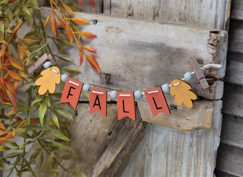 Our Fall Mini Clip Banner is a strand of wooden beads and tags with a mini clothespin at each end. This versatile accent piece can be clipped onto a tiered tray, a wreath, and more to add a festive touch of Fall. Measures 9" long by 1.5" tall. - Material: Wood - Size: 1.5" H x 9" L - Color: Orange, Yellow, Gray, Brown - Designer: Michelle Kildow Fall Tier Tray, Fall Tray, Wood Banner, Pennant Garland, Thanksgiving Banner, Fall Banner, Outdoor Gifts, Pennant Banner, Fall Mini