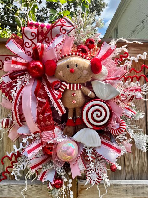 The Gingerbread Candy Pink White and Red theme is so popular for the holidays.  It is so whimsical and fun to display in your home at Christmas time.         This wreath has an evergreen base and red , pink and white mesh.  I embellished the wreath with loads of lollipops, candy canes, gingerbread cookies, a Gingerbread man wearing ear muffs posing with huge swirly peppermint candy, frosted white greenery, and red iridescent pink and white ornaments.   I also added a deluxe gingerbread themed bow made out of designer ribbons.      Everyone will love this wreath when you have it displayed in your home, your front door, porch, or as a wall hanging in your home.  It would make an excellent Christmas or Housewarming gift.  I use high quality products to create my designs. As with all of my wre Pink And Red Gingerbread Christmas Tree, Christmas Wreaths Pink, Pink Red And White Christmas Decor, Red And Pink Christmas Decor, Pink Peppermint Christmas, Pink Christmas Ideas, Gingerbread Wreaths, Candy Wreath Christmas, Pink And Red Christmas