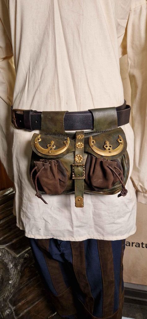 Decorated with beautiful gold-tone metal hardware, this leather kidney pouch will impress those around you with ease. An ornate buckle closes the flap securely and reliably. The intricately designed pouch is well-suited to a range of historical and fantasy concepts, particularly for wealthy merchants or nobles. - Can be worn on the belt to keep belongings close at hand - Made of leather for an authentic look and robust quality - Dimensions: Width: 24 cm, Height: 15 cm Medieval Bags, Brass Fittings, Metal Hardware, Adult Costumes, Gold Tone Metal, Belt Bag, Bags Designer, Gender Neutral, Bathing Beauties