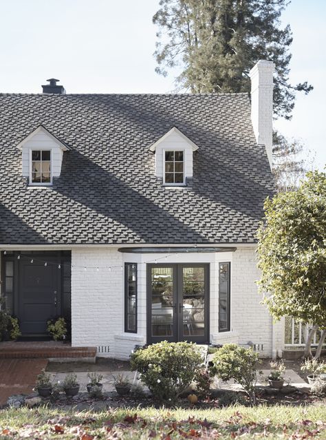 The red brick exterior—with its original slate roof—was given a fresh guise courtesy of white paint and black-framed windows, including new French doors in the bay window. Bay Window Exterior, Red Windows, Red Brick Exteriors, Framed Windows, Exterior House Paint, Storybook House, Midcentury House, Estate House, Exterior Inspiration