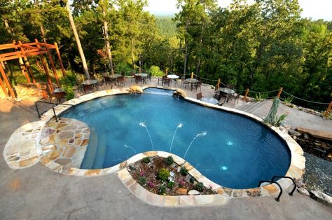 This cozy kidney bean shaped pool stands upon an expansive concrete patio with soaring forest views, wrapped in flagstone. A small fountain to the right complements a garden at center. Bean Pool, Awesome Backyards, Swimming Pool Cost, Pool Plans, Treehouse Resort, Kidney Shaped Pool, Concrete Swimming Pool, Pool Cost, Building A Swimming Pool