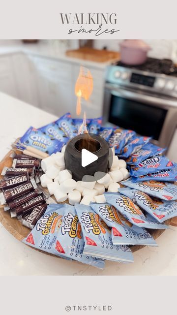 Tara Tedesco | Tnstyled on Instagram: "WALKING S’MORES BOARD!   Comment SMORES and I’ll send you my mini fire pit! It also comes with cute little sticks to roast marshmallows. If you guys have seen the “walking” tacos this is a take on that that I have seen a few times! Had to try it out and I can confirm it’s such a fun idea!   I added a bunch of cookies, chocolate and marshmallows to a board along with the mini firepit. You can change this up and use different candy and cookies!   #summerideas #summertime #smores #camping #vacation" Walking Smores In A Bag, Smores Charcuterie Board Ideas, Walking Smores, Smores Charcuterie Board, Diy Smores Bar, Goonies Halloween, Smores Ideas, Christmas Tent, Smores Bars