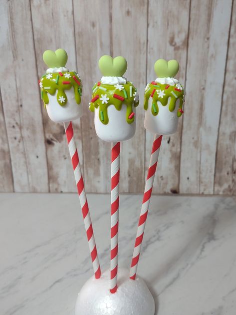 "Faux marshmallow GRINCH-themed lollipops. Green chocolate dipped and whipped topping with candy sprinkles.  Decorate your Grinchmas tiered tray or holiday decor!  This listing is for ONE Grinch Pop. FREE Gift wrapping and note from sender option.   Intended for display, not to eat! Measures approximately 1 1/4\" wide and 10\" tall. Carefully packaged, padded, and shipped with care.   Willing to bundle, message me with any questions!" Christmas Chocolate Lollipops, Diy Marshmallow Ornaments, Grinch Dessert Table, Grinchmas Treats, Grinch Cakesicles, Grinch Marshmallow, Grinch Christmas Diy, Grinch Truffles, Grinch Christmas Decorations Diy