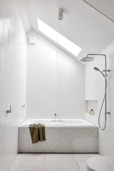 The terrazzo flooring in this bathroom travels through the shower and wraps onto the surround of the built-in bathtub. White Corian Countertops, Terrazzo Bathroom, Bathroom 2024, Built In Bathtub, Corian Countertops, Built In Bath, Wood Shelving Units, Modern White Bathroom, Louver Windows