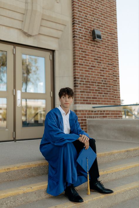 Male in blue gown holding graduation cap on steps of school. Cool Graduation Pictures For Guys, Cap And Gown Senior Pictures For Guys High Schools, Guy Cap And Gown Pictures, Male Cap And Gown Pictures, Boy Cap And Gown Pictures, Guys Graduation Pictures, Cap And Gown Senior Pictures For Guys, Guy Graduation Pictures, Graduation Poses For Guys