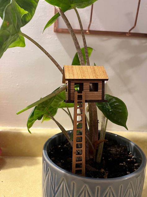 This mini treehouse is exactly what you need for your plants! it is 3 in by 3 in so it fits in any house plant without overwhelming it. it comes with one house fully assembled, a clear plastic stake for placement and a wooden ladder. this makes the perfect unique gift! Plant Treehouse, Mini Treehouse, Mini Tree House, Treehouse Decor, Tiny Items, Fairy Garden Pots, Tree House Designs, Inside Plants, Wooden Ladder