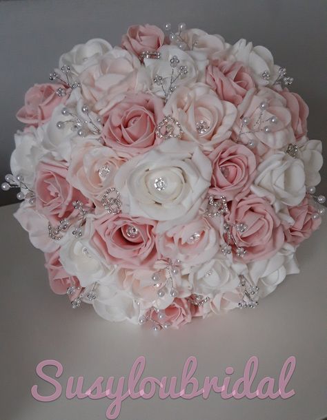 "A Beautiful, Romantic Fairytale Bouquet in two tone Dusky Pinks and White Roses with a large diamante in each Rose. It has White Pearl sprays, Silver and White Bead Cluster Sprays and Diamante Hearts throughout this Bouquet. The Roses are foam and are completely colourfast. The handle is covered in quality Dusky Pink Satin with Two Bows either side of the handle and finished with Diamante trim at the top of the handle. This Bouquet looks and feels gorgeous and has been made to a very high stand