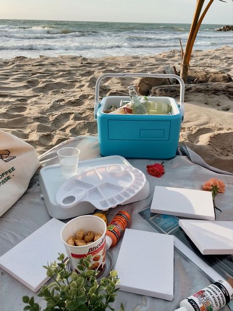 Beach picnic, with painting materials as canvas, paint, brushes, ice chest with cold drinks, and flowers Beach Paint And Sip, Beach Picnic Painting, Paint Picnic Aesthetic, Painting On The Beach Date, Paiting Aesthetic Date, Picnic Painting Ideas, Beach Date Ideas, Beach Picnic Ideas, Picnic Painting