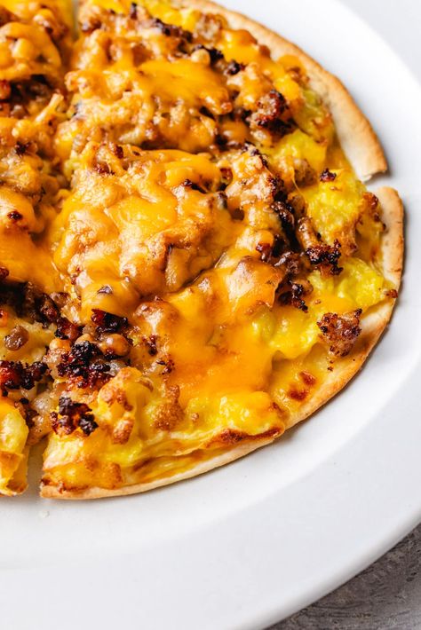 Enjoy a protein-packed start to your day with this delicious Breakfast Pizza Recipe. Featuring low-carb tortillas as our pizza crust, a cheesy, creamy sauce, scrambled eggs, crumbled sausage, shredded cheese, and any extra toppings you desire. High Protein Breakfast Pizza, Tortilla Breakfast Pizza, Egg Pizza Breakfast, Breakfast Pizzas, Breakfast Tortilla, Egg Pizza, Protein Pizza, Breakfast Pizza Recipe, Egg Protein