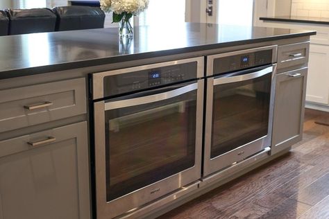 A picture of two single ovens in an island. Double Oven Island, Two Wall Ovens Side By Side, Kitchen Wall Oven Ideas, Microwave And Oven In Island, 4 Ovens Kitchen, Oven Built Into Island, Kitchen With 2 Ovens, Kitchen Island With Slide In Range And Seating, Kitchen Layout Ideas With Island Double Ovens