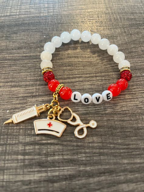 "Because we love our nurses we created this bracelet of white Quartz beads, red beads, rhinestone beads and spacers and of course the \"Love\" beads along with 3 different gold plated nurse charms.  It is a size 7 but can be adjusted upon request." Nurse Clay Bead Bracelet, Accesorios Aesthetic, Preppy Bracelets, Diy Jewelry Unique, Gift Inspo, Bead Charms Diy, Red Beads, Bangle Bracelets With Charms, Bracelet Ideas