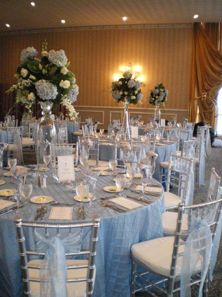 light blue wedding theme- light blue table linens, blue accents in the flower centerpieces, and light blue tulle on silver chairs Sky Blue And Silver Wedding, Blue And Silver Wedding Decorations, Blue Quinceanera Theme, Baby Blue Quinceanera, Ice Blue Weddings, Cinderella Quinceanera Themes, Light Blue Quince, Blue And Silver Wedding, Cinderella Wedding Theme