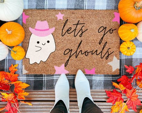 "Looking for a fun Halloween doormat to display at your home this spooky season? This handprinted coir doormat will be sure to put a smile on your guests faces! This mat features a cute ghost with a pink cowgirl hat, pink and silver stars, and the words \"lets go ghouls\"; a play on words from the hit country song \"Man, I feel Like A Woman\".  This pink country western aesthetic is super fun and would be a hit amongst your friends this fall season!  Our coir doormats have a vinyl backing that a Spooky Rugs Diy, Coffin Porch Sign, Winter Door Mat, Diy Halloween Doormat, Cute Halloween Decorations Outdoor, Fall Stencils, Ghost Cowboy, College Crafts, Doormat Ideas