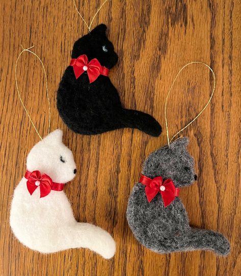 Thank you for visiting my shop. Donna This listing is for handfelted cat ornaments. The kitties are available in black, gray, or white. Each is a 2 dimensional felted cat, but it is of substantial thickness. It measures 4  inches to top of ears, and 4 inches from nose to tail. It is a full 3/8 inches thick.  The cats are felted from all natural fibers including llama and merino wool.  they are decorated with a red ribbon collar and tiny bow accented with a white pearl.  They have a fine gold cho Wool Christmas Tree Ornaments, Christmas Cat Ornaments, Felted Christmas Ornaments, Diy Felt Christmas Ornaments, Felted Christmas, Ribbon Collar, Felted Cat, Needle Felted Christmas, Felt Crafts Christmas