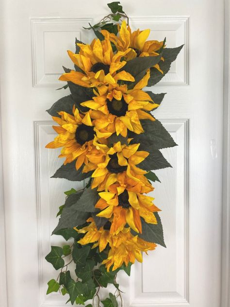 It is time to look toward fall. Without going all fall leaves and pumpkins, a sunflower and daisy swag is a nice late summer swag to cheer passers by.   Use a block of styrofoam roughly the dimensions as the one above. About 12 inches long by 4 inches wide and 2 inches thick.   I began pushing wire through the piece of styrofoam to make my hook to hang my swag from. If you don’t put something beneath the wire, it will pull all the way through and cut the styrofoam. I cho… Sunflower Swag, Fall Leaves And Pumpkins, Sunflower And Daisy, Diy Swag, Easy Fall Wreaths, Backyard Flowers, Swag Wreath, Door Swag, Summer Swag