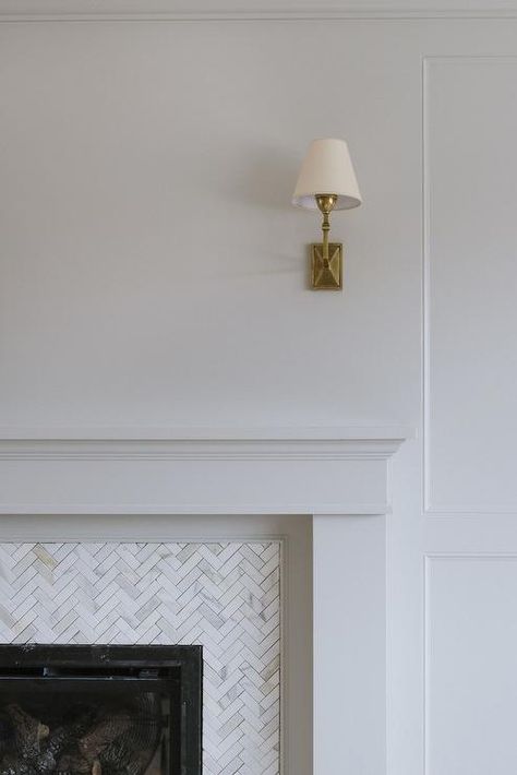 A Jane Wall Sconce is mounted above a white fireplace mantel fixed framing carrera marble herringbone surround tiles. Herringbone Tiles Fireplace, Herringbone Fireplace Surround, Herringbone Tile Fireplace, White Fireplace Mantel, Studio Mcgee Fireplace, Herringbone Fireplace, White Fireplace Mantels, Fire Surrounds, Vancouver House