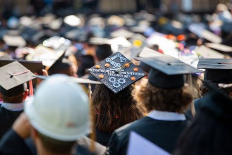 A graduate sits at summer commencement with a decorated grad cap that  says "Mechatronics Engineering Technology" with mechatronic symbols around it. Car Themed Graduation Cap, Mechanical Engineer Graduation Cap, Robotics Graduation Cap, Civil Engineer Graduation Cap, Electrical Engineering Graduation Cap, Mechanical Engineering Graduation Cap, Engineer Graduation Cap, Engineering Graduation Cap, Engineering Graduation