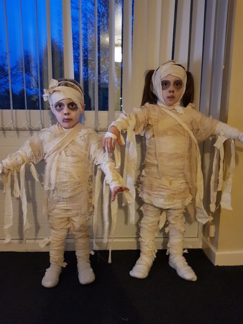 My DIY cheap no sew mummy costume!   * rip up an old bed sheet * use tea water to stain * then dry * use a hot glue gun to glue small pieces onto old white clothes * then when the costume is on, simply wrap longer pieces for added effect. * use old white socks to cover shoes and wrap those too! Mummy Costume Kids, Mummies Costume, Mummy Makeup Halloween, Diy Mummy Costume For Kids, Mummy Fancy Dress, Mummy Costume Diy, Easy Mummy Costume Diy, Mummy Diy Costume, Halloween Costumes Mummy