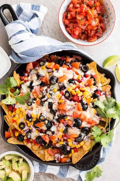 This loaded vegetarian nacho recipe has it all: The best Southwestern/Mexican flavors from black beans in chili sauce, cheese, olives, corn, tomatoes, sweet peppers and cilantro! They are quick and easy to make, baked in a skillet in the oven, full of healthy vegetables and great to feed a crowd at summer parties, on football sunday or for super bowl. Serve with a light dip and some fresh avocado! | #recipe #easyrecipes #nachos #mexican #cincodemayo #appetizer #footballfood Vegetarian Nachos Recipe, Loaded Nachos Recipe, Favorite Party Appetizers, Vegetarian Nachos, Nachos Recipe Easy, Loaded Nachos, A T, Appetizers For A Crowd, Tips To Save Money