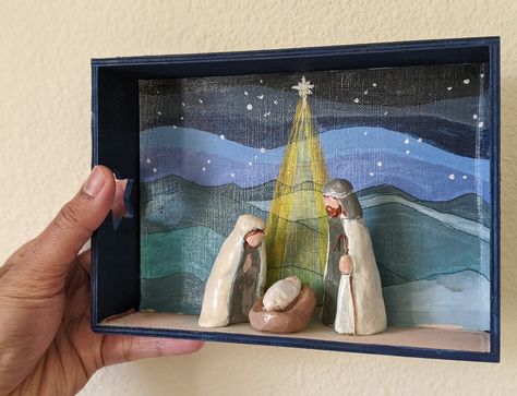 Hand-sculpted clay nativity set with blue stary night backdrop, all composed in a 7" x 5" wooden shadow box.  - Its a simple presentation of nativity with shades of blue and green backdrop which gives a contemporary feel to the scene. - Each piece will be unique since handmade.  - Whether a Christmas gift, a wedding gift or self-purchase, it reflects hand-sculpted simplicity and a perfect representation of family holiday tradition.  Handmade in air dry clay painted in acrylics and finished with Clay Nativity Set, Clay Nativity, Nativity Scene Diy, Simple Presentation, Nativity Silhouette, Clay Decor, Holiday Traditions Family, Diy Nativity, Art Backdrop