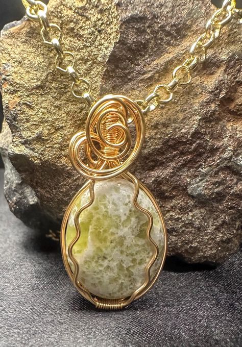 Green and White Serpentine Wire Wrapped Pendant. I wrapped this pendant in gold colored tarnish resistant copper wire. I tumbled and hand polished this stone to show off the beautiful green spots. Serpentine is one of my favorite gemstones to tumble and polish. As serpentine has a naturally waxy shine, I buffed this stone with beeswax to enhance the shine. Noble Serpentine, also known as Healerirte directs life force where healing is needed, helps align the body, may relieve back pain, counterac Green Stone Necklace, Natural Stone Necklace, Natural Stones Necklace, Tumbled Stones, Wrapped Pendant, Wire Wrapped Pendant, Green Stone, Green And White, Stone Necklace