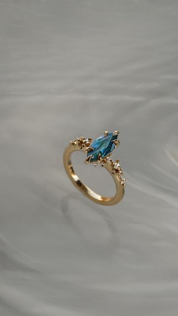 Laurie Fleming on Instagram: "A fragment of the clearest summer sky, captured upon this Bespoke Nereid Ring🦋 A truly one of a kind teal marquise cut sapphire held in 6 of our signature claw prongs and encapsulated by petite diamond clouds☁️   Already at her forever home, but we would love to work with more marquise cut sapphires! Email us or submit our online Bespoke Form to inquire about your own." Marquise Aquamarine Ring, Marquise Sapphire Ring, Marquis Engagement Rings, Laurie Fleming, Jade Engagement Ring, Marquise Sapphire, Gems Ring, Ring Inspo, Claw Prong