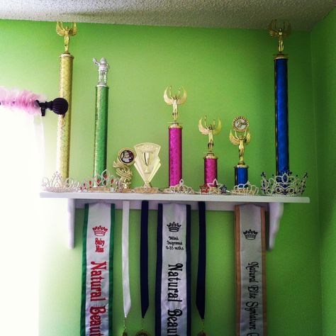 Her winnings so far! 8 months into her pageant career! Super cheap shelf from Hobby Lobby ($8 with 40% off coupon), white spray paint, and sticky Velcro to hold on the medals and sashes. Pageant Crown And Sash Display, Pageant Trophy Display Ideas, Crown And Sash Display, Pageant Room, Pageant Crown Display Ideas, Beauty Pagents, Awards Display, Crown Display, Pageant Sashes