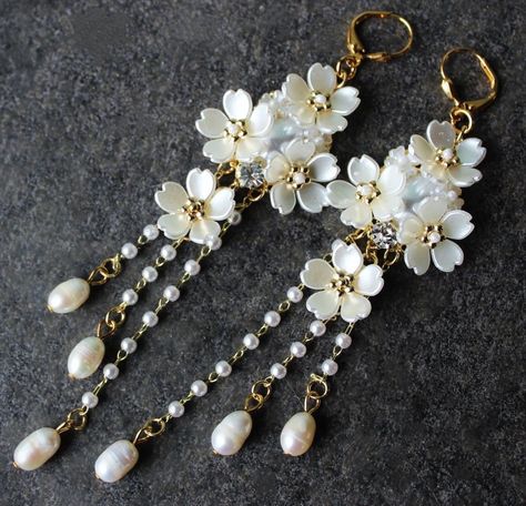 This is a statement earrings. Elegant, opulent, and shimmery, this show stopping earrings feature a soft, rich palate. The bottom fringe features three strand of small white freshwater pearls. Dangle off a sculpted white shell flowers cluster jeweled with Swarovski Crystals, plated in gold. This earrings measure 4" in length. Earrings are light weight and sway gracefully as you move about your day. These luxury earrings are bold and beautiful, and make a powerful statement. These stunning chande Wire Jewelry Earrings, Shell Flowers, Gelang Manik-manik, Pretty Jewelry Necklaces, Gelang Manik, Luxury Earrings, Crystal Dangle Earrings, Clay Jewelry Diy, Earrings Elegant