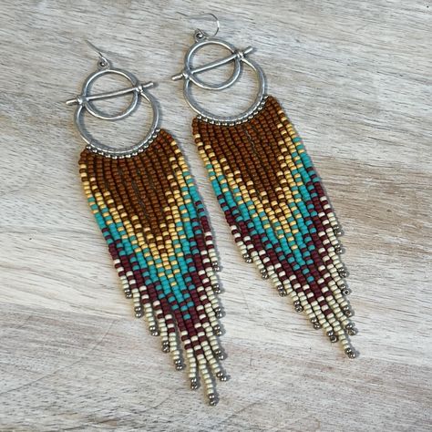 Beaded fringe earrings in rust, turquoise, red, and yellow tones, suspended from silver hoops. Details~ * Made with glass seed beads and sterling silver ear wires, suspended from silver plated alloy frames. * Length: Drop length (including ear wire) is approximately 12 cm. Width is slightly under 3 cm.  * Packaging: Your order will arrive lovingly packaged in a gift box, wrapped with a ribbon and ready for gifting. * Please visit my Etsy shop for a full selection of my handmade jewelry: https:// Indigenous Beading, Stitch Earrings, Beading Jewelery, Brick Stitch Earrings, Beaded Tassel Earrings, Yellow Tones, Southwestern Style, Beaded Fringe, Orange And Yellow