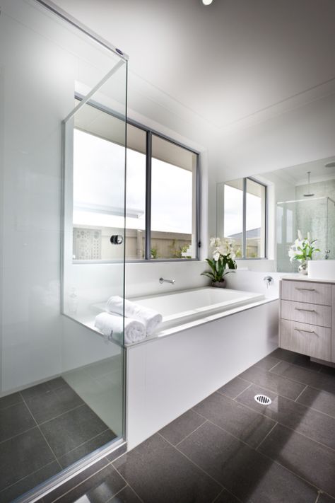 This bright bathroom features large format brown tile flooring and white walls and bath surround. Light wood cabinetry on the vanity adds a layer of detail, as does glass enclosed shower. Long Bathroom Layout, Long Narrow Bathroom Ideas, Dark Floor Bathroom, Colorful Bathroom Tile, Gray And White Bathroom, Grey Bathroom Tiles, Changchun, White Tub, Bathroom Floor Plans