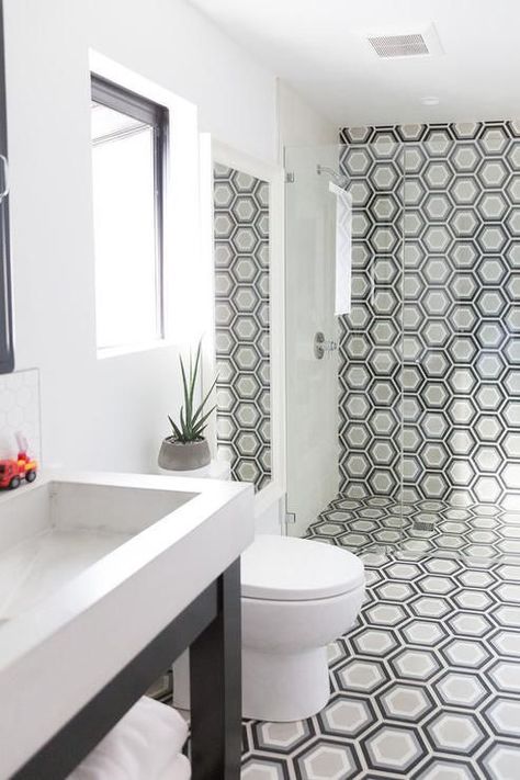 A black washstand finished with a white porcelain sink sits on black and gray hex floor tiles that continue up an accent wall in a seamless glass shower fitted with a polished nickel faucet kit mounted to light gray shower wall tiles. Kids Bathrooms, Shower Wall Tile, Tiles Ideas, Bathroom Plans, Transitional Bathroom, Bathroom Shower Tile, Hexagon Tiles, Bathroom Pictures, Bathroom Tiles