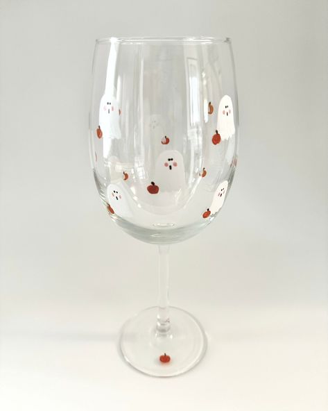 This cute Ghost wine glass has a small pumpkin and is a Halloween gift ready to give as a hostess or birthday gift!  There are 12 white ghosts and 12 little orange pumpkins that are hand painted on each glass.  Fall decor with a Minimalist design.   The glass is 9 inches tall and holds 19 oz.   I use high quality enamel glass paint.  Double painted and heat cured. Hand washing is recommended for years of beauty.   Gift box included with a hand written notecard. Glass Painting Designs Halloween, Halloween Diy Wine Glasses, Pumpkin Painted Wine Glasses, Ghost Wine Glass Painting, Ghost Glass Cup, Halloween Glasses Diy, Fall Painted Wine Glasses Diy, Painting Glassware Diy, Halloween Glass Painting Ideas