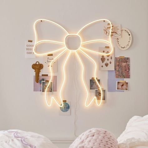 Tie your room together with this whimsical neon sign. White LED bulbs trace a glowing bow silhouette, adding an enchanting accent to your sleep space. Designed exclusively for Pottery Barn Teen by lifestyle brand LoveShackFancy. KEY PRODUCT POINTS Made of iron, plastic and LED. Plug-in. 5 volts. Mounting hardware included; screw. Imported. Decorative Ideas For Bedroom, Women’s Room Decor, Pink And White Preppy Room, Coquette Led Lights, Preppy Led Lights, Cute Girly Room Ideas Bedrooms, Must Have Room Items, Cute Pictures To Hang In Your Bedroom, Cute Pastel Room Decor