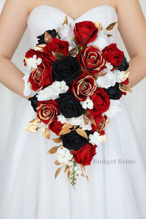 This lovely assortment of beautiful flowers is bound to turn heads on your wedding day. This lovely cascading brides’ bouquet with red roses with gold glitter tips, red, black and white roses is an absolutely breathtaking arrangement for any bride to be, in any season. Gold foliage complete the look and add a delicate realism to this beautiful bouquet. This bouquet is 10” wide, 18” long, and is crafted by our in-house florists without using a foam base to anchor the flowers to the bouquet. Inste Red Black And Gold Wedding Bouquet, Black And Red Winter Wedding, Red Black And Cream Wedding, Red N Black Wedding Theme, Black N Red Wedding Ideas, Elegant Black And Red Wedding, Black Wedding Bouquet Color Schemes, Red Gold And Black Wedding Theme, Red Black And White Bouquet