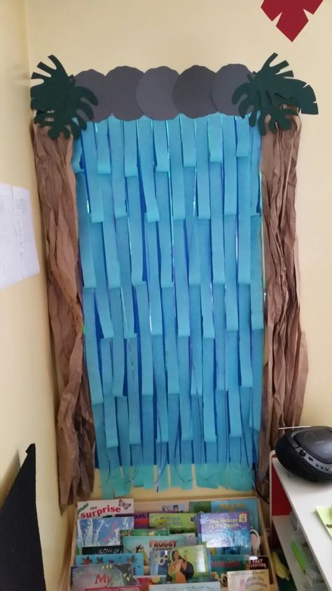 Diy Waterfall for Rainforest theme classroom. Streamers and shiny ribbon for water, brown packaging paper, and cardstock used to make leaves and rocks. Waterfall Classroom Decoration, Rainforest Classroom Transformation, Rainforest Room Ideas, Diy Waterfall Decoration, Rainforest Theme Classroom, Rainforest Decorations, Aquatic Biome, Rainforest Display, Jungle Classroom Theme