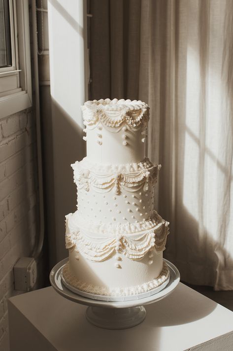 A white three tiered wedding cake with vintage swap piping and polka dots Traditional Wedding Cake Piping, Wedding Cake White Piping, Wedding Cake Aesthetic Simple, Wedding Cake Tiers Sizes, Vintage Theme Wedding Cake, Vintage Wedding Cake Just Married, White Tiered Wedding Cake, Old School Piping Wedding Cake, Three Tier Vintage Cake