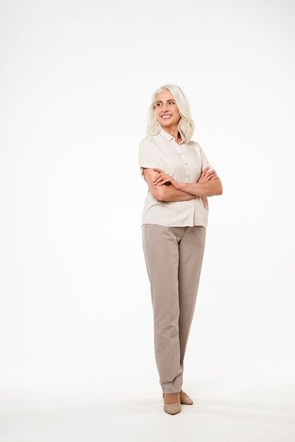 Premium Photo | Photo full length portrait of beautiful adult woman 70s with gray hair smiling and looking with arms in pockets, isolated over white wall Stock Images People, White Backround, Logo Reference, Folded Arms, Reference Ideas, Clothing Board, Smile Images, Middle Aged Women, Pose References