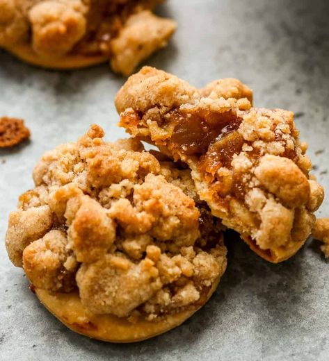 Three apple pie cookies set on a counter, two stacked on each other, the top cookie with a bite taken out showing the flaky pie crust, apple pie filling and streusel. Apple Pie Cookie Recipe, Stewed Apples, Pie Crust Cookies, Pie Crust Uses, Autumn Dessert, Apple Pie Cookies, Buttery Pie Crust, Bite Size Cookies, Slice Of Pie