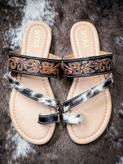 The Greta Lee Sandals are the best of both worlds - a little bit of hide and a little bit of tooling. Pair these with any outfit to show your western side! Featuring two straps crossing over the top of the foot, one adorned with authentic cowhide, and a single toe strap, these sandals exude frontier allure with a touch of urban edge. The cowhide strap adds a distinctive Western flair, evoking images of open plains and rugged landscapes. With a comfortable leather footbed, these sandals pro... Greta Lee, Over The Top, Sandals, Leather, Quick Saves