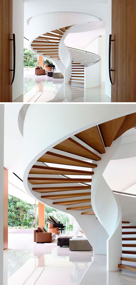 A grand spiral staircase created by floating wood treads between the two white sides rises up into the next floor and welcomes people as they enter the home. Spiral House, Staircase Spiral, سلالم حلزونية, Stairs Interior, Modern Staircases, Spiral Stair, Beautiful Stairs, Escalier Design, تصميم للمنزل العصري