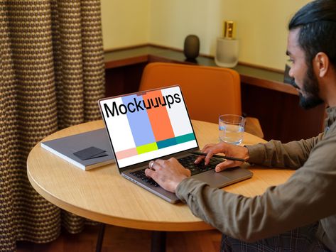 Discover our versatile MacBook Pro mockup, perfect for showcasing your app or website. In this cozy lounge setting, a man is typing on a MacBook Pro at a round wooden table. The table features a notebook and a glass of water, creating a realistic workspace setting. The background includes an orange chair, a curtain with a checkered pattern, and a modern lamp. Easily replace the screen contents with your own designs. Ideal for presenting UI/UX projects in a professional yet relatable environment. #Mockup #UI #UX #Design #Workspace #MacBookPro Modern Office Lounge, Design Workspace, Round Wooden Table, Computer Mockup, Macbook Mockup, Billboard Mockup, Orange Chair, Ipad Mockup, Digital Lifestyle