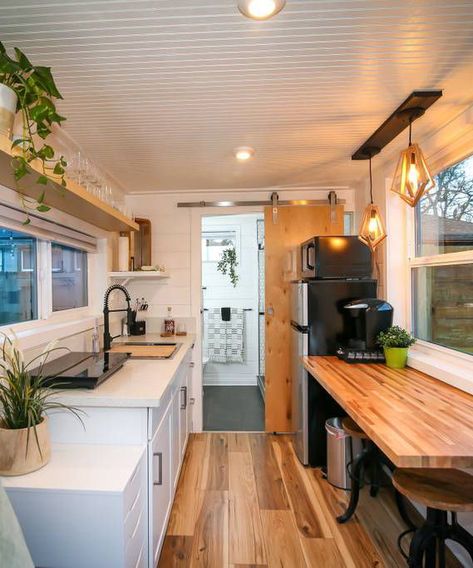 The kitchen includes a refrigerator, microwave convection oven, induction cooktop, and Kuerig coffee machine. It is also equipped with pots, pans, and other kitchen essentials. Container Van House, Container House Interior, Shipping Container House Plans, Shipping Container Home, Tiny House Kitchen, Van Home, Container House Plans, Casa Container, Modern Tiny House