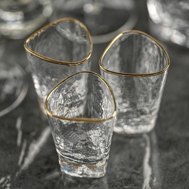 Featuring a glittering gold rim and textured glass that refracts light, this collection adds an exuberant sparkle to any tablescape. A glass for every style of tequila, the gold rim shot glasses will bring a touch of luxury to your bar. Sold in Set of 6 Clear hammered lead-free glass Unique ergonomic gold rim which is easy and comfy to drink from Material: Glass Color: Gold, Clear Dimensions: 2"D x 3"H Capacity: 71 ml/ 2.4 oz Care: Hand wash only. Shot Glass Set, Live Beautifully, Highball Glass, Touch Of Gold, Deco Table, Glass Texture, Custom Upholstery, Shot Glasses, Joss And Main