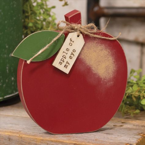 Our Apple of My Eye Wooden Apple Sitter is an apple-shaped wood block with an engraved wooden tag and a jute bow. This piece is ideal for gift giving, Fall table layering, or as a year-round accent. This freestanding piece measures 6" wide by 6" high by 0.75" thick. - Material: Wood - Size: 6" Dia. x 0.75" D - Color: Dark Red, Tan, Green - Designer: Suzie Pienta #teacherappreciationgifts Wooden Apples Crafts, Wooden Apples Decor, Apple Silhouette, Wood Apples, Apple Craft, Apple Decorations, Teacher Apple, Wooden Tags, Wooden Cutouts