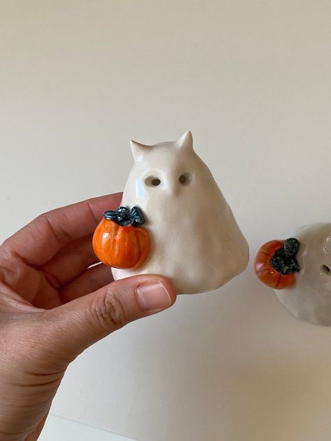 Discover the charming Handmade Ceramic Mini Cat Ghost, carrying tiny fish in a pumpkin-shaped basket. This adorable ghost figurine is perfect for adding a whimsical touch to your home decor or as a delightful gift for cat lovers. 🎨 All of my ceramic items are designed, hand-built, and hand-painted by me. I hand-shaping and fire them to 2000 oF in a ceramic kiln. Then I glaze them by hand-painting and fire them for a second time.  Due to the 100% handmade nature of the items, small imperfections are expected. This makes every piece unique and gives them character.  📍 Product Information:  - Resistant to impact and scratches.  - Delivered with safe and guaranteed delivery.  - The price is for 1 piece.  - Height 5/7 cm  📦 Shipping: We work with the Express services of the world's leading c Mini Ceramic Sculptures, Pottery Halloween, Ghost With Pumpkin, Pumpkin Basket, Ceramic Kiln, Tiny Fish, Cat Ghost, Miniature Pottery, Halloween Clay